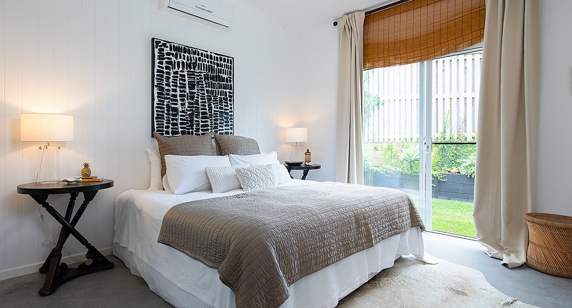 large bedroom with a brown and white bed, two side tables and modern artwork hanging on the wall
