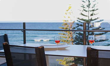 Two wines of bright red wine on a table facing the ocean