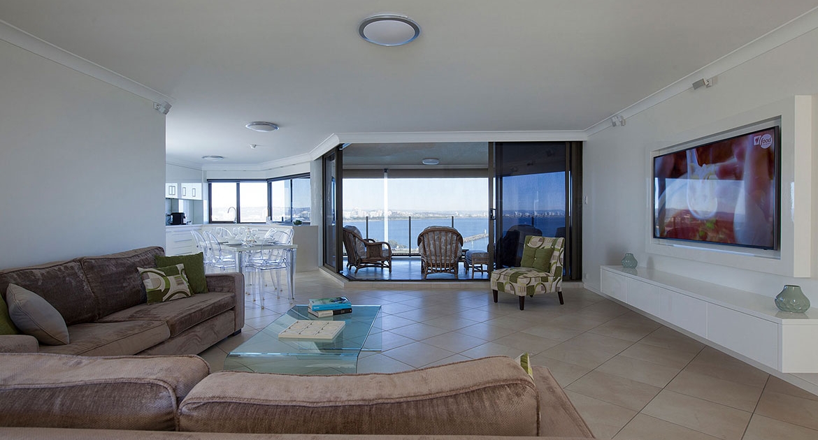 Spacious living room with massive wall mounted flat screen tv with access to outdoor entertainment area at Cartwright Beachfront Apartment | Sunshine Coast Holiday Rentals