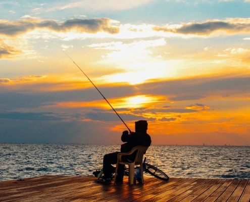 Guy fishing at the beach during a beautiful sunset | Featured image for Best Places to go Fishing Sunshine Coast | Blog